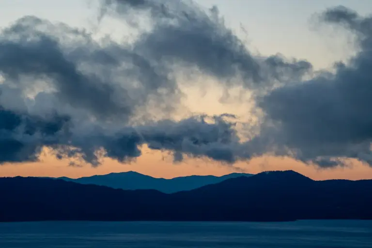 dark clouds over Lake Tahoe and layered mountain ridges at sunset